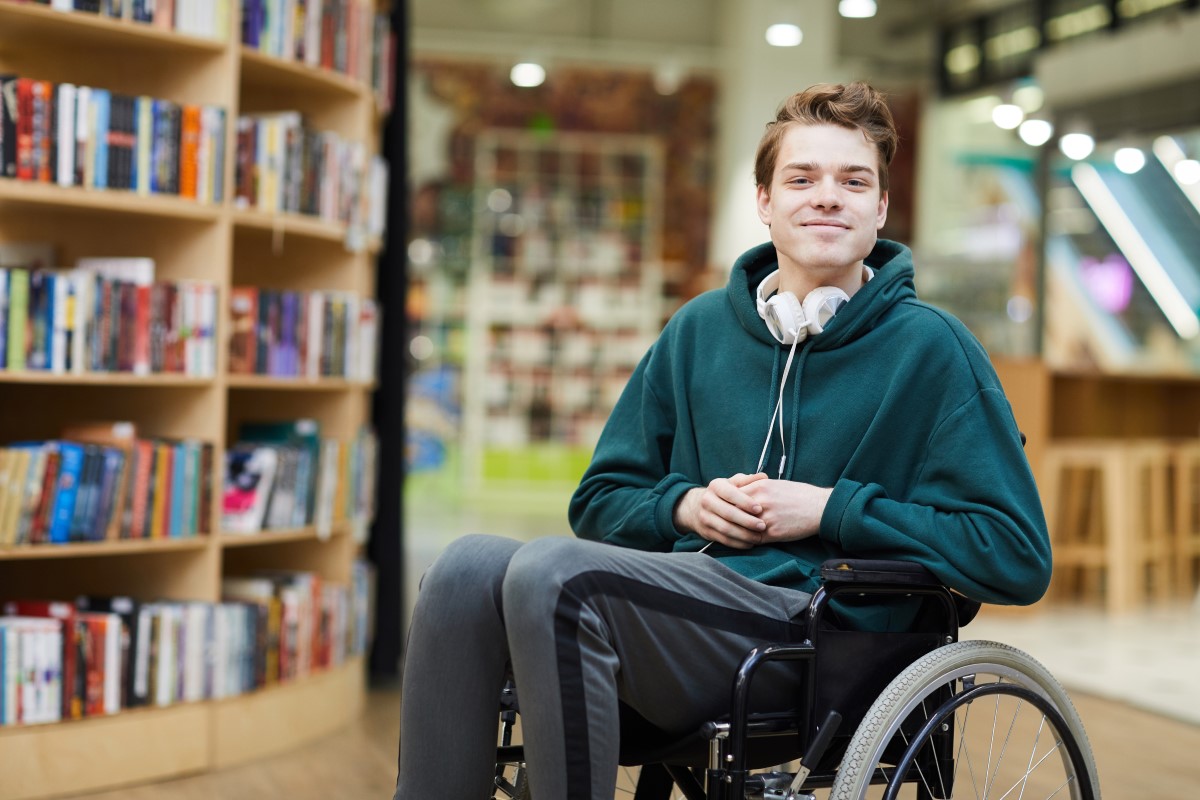 Etudiant en fauteuil roulant, dans une bibliothèque