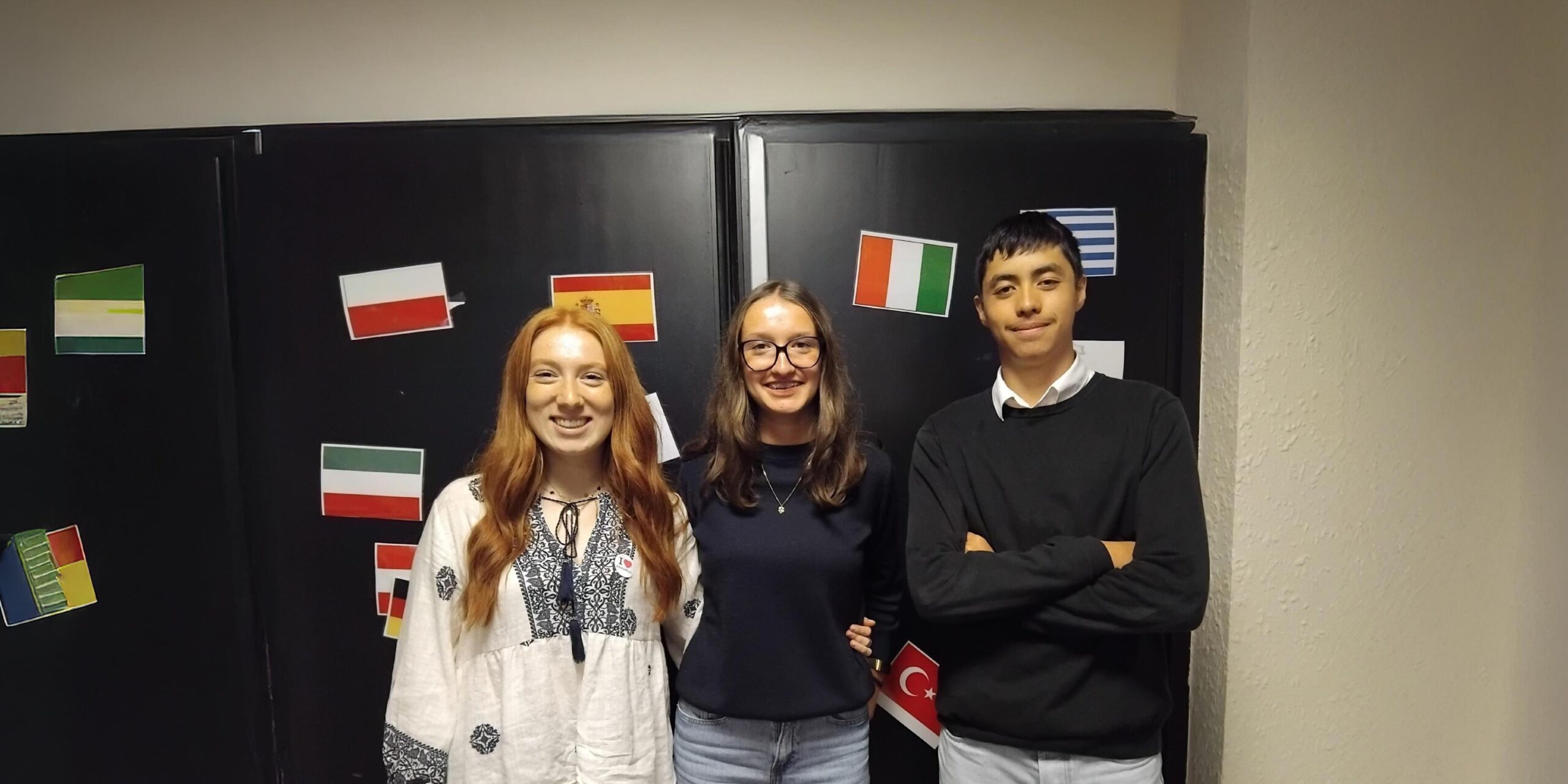 Trois élèves d'un lycée agricole partis en mobilité Erasmus+ posent devant un mur qui a été décoré avec des drapeaux de pays européens
