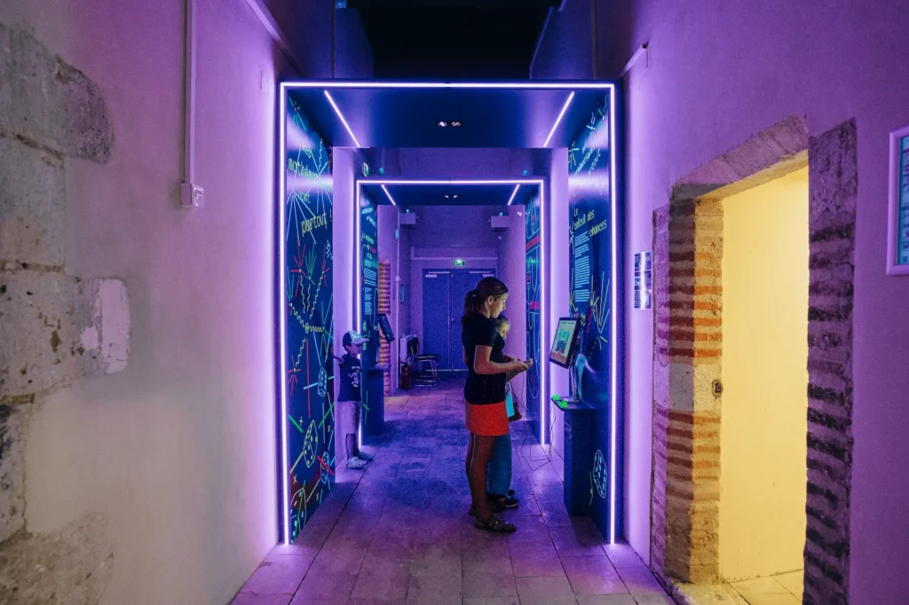 Une femme et deux enfants dans un couloir du musée, devant un écran